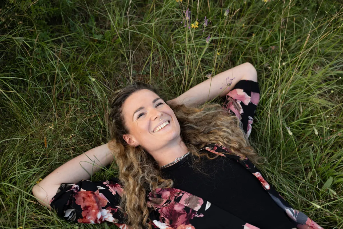 Nadja Hollstein liegt lachend in einer Wiese